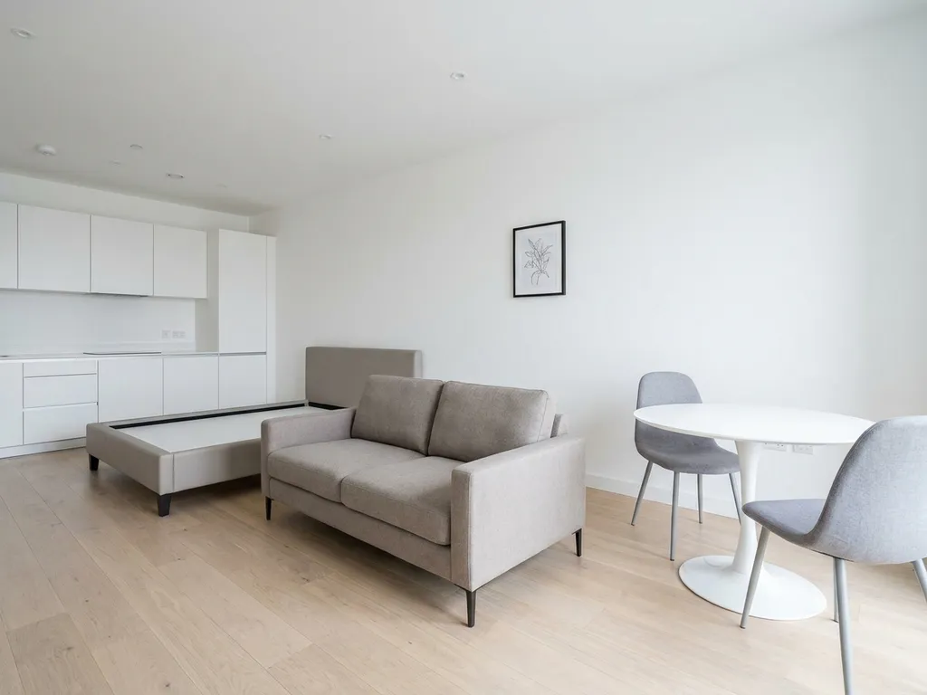 Minimalistisch eingerichtete Wohnung mit greigefarbenem Bett, weißem Tulpen-Esstisch und hellem Eichenparkett.