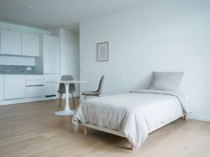 Minimalistisch möbliertes Apartment in Hannover mit hellem Holzboden, weißer Küche und rundem Tulpen-Esstisch.