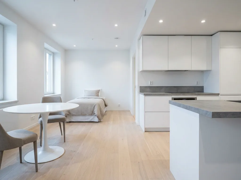 Minimalistisch eingerichtete Wohnung mit hellem Parkettboden, weißer Einbauküche, grauer Arbeitsplatte und rundem Tulpen-Esstisch.