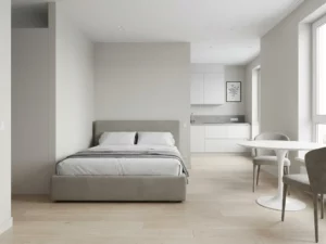 Minimalistisch eingerichtetes Apartment mit greigem Bettgestell, rundem Tulpen-Esstisch und hellem Eichenparkett.